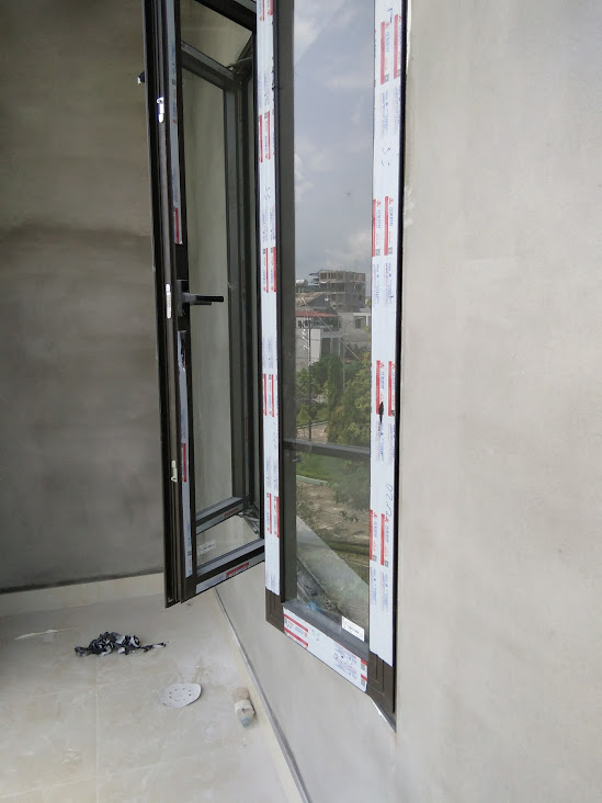 Cửa sổ nhôm kính mở hất màu đen mới lắp đặt trong phòng đang hoàn thiện